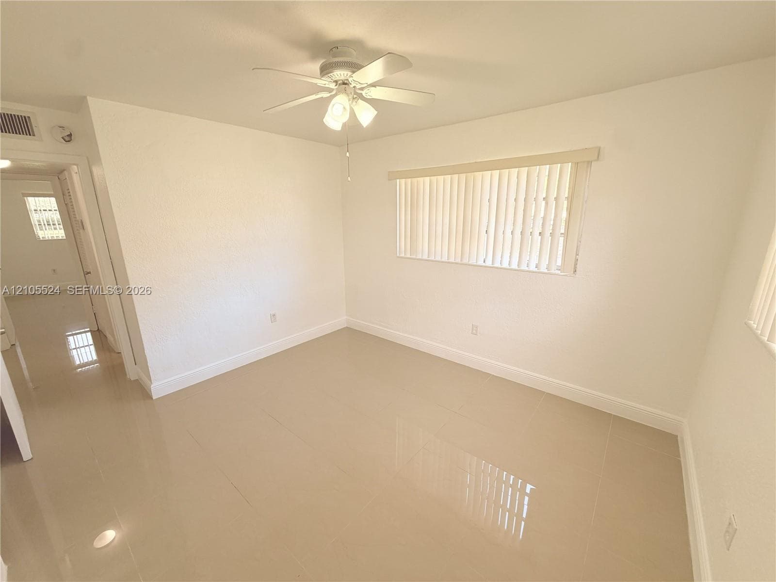 Smooth tile flooring, white walls, and a ceiling fan with integrated lighting
