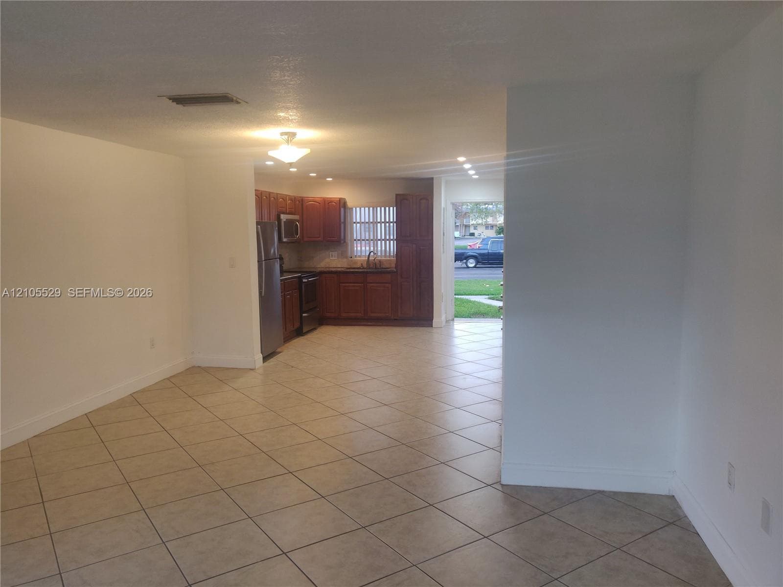 Tile flooring throughout, recessed lighting, wood-finish cabinetry, stainless steel appliances, and a single basin sink