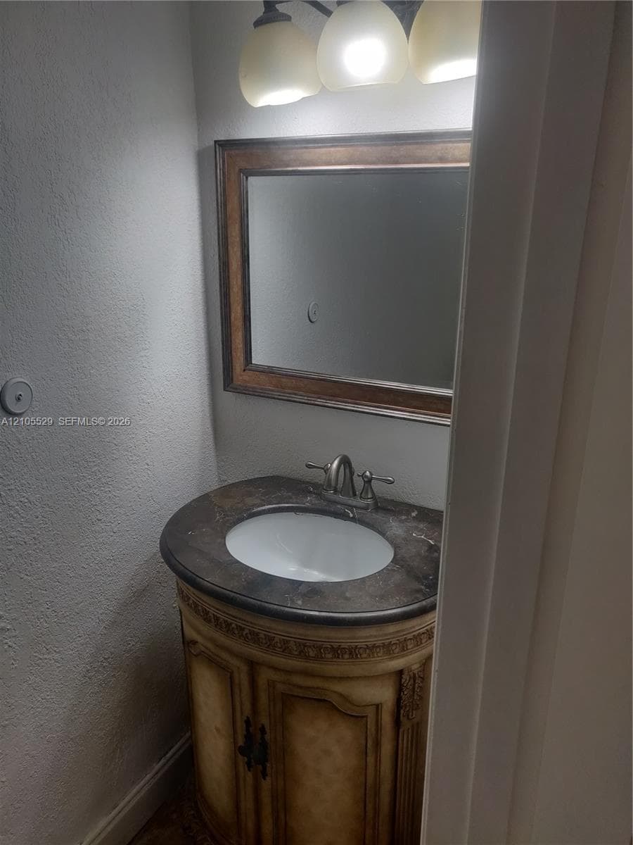 Curved vanity with an integrated sink, framed mirror, and a three-light fixture