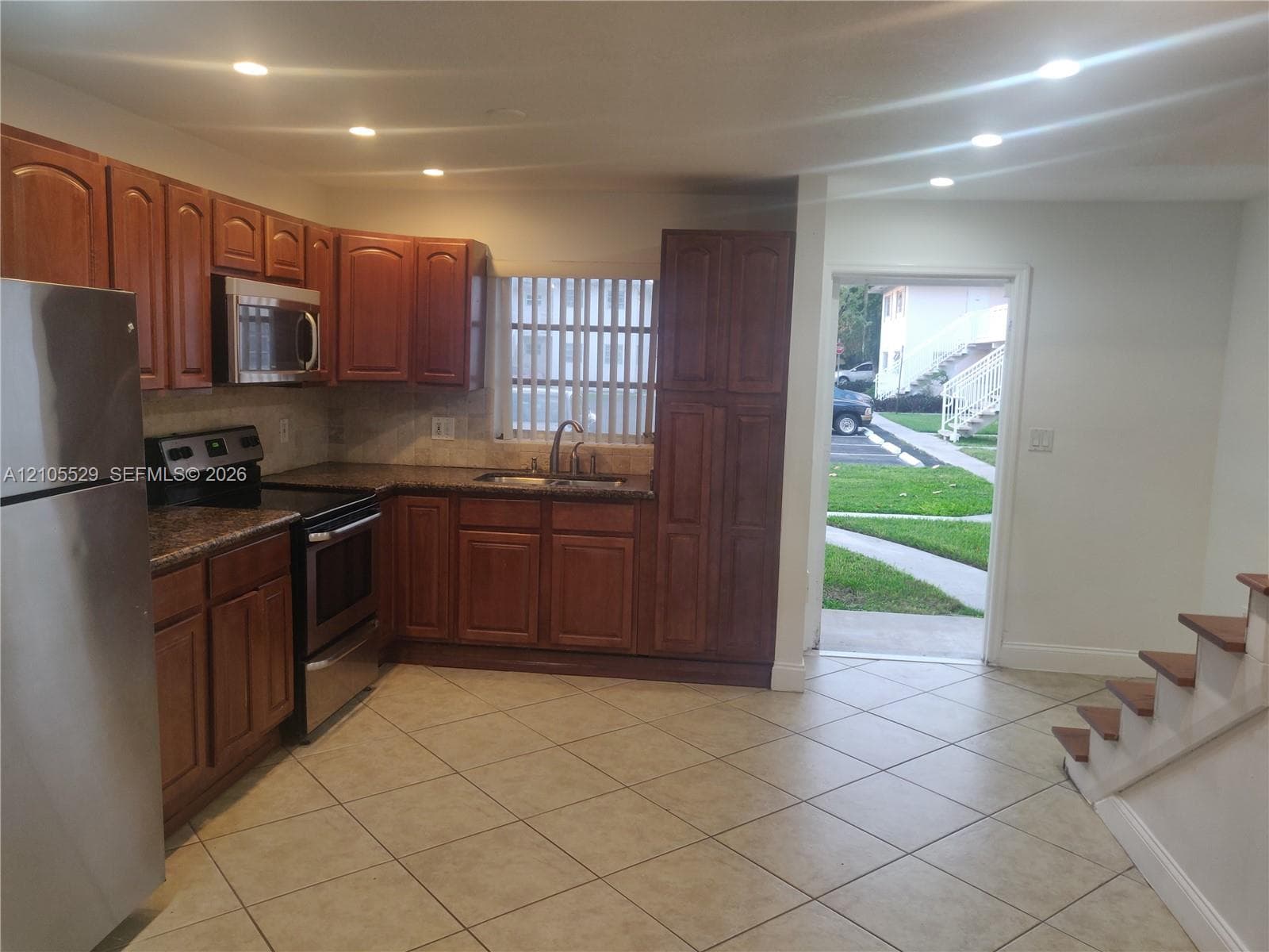 Kitchen featuring wood-finish cabinetry, stainless steel appliances, and tile flooring