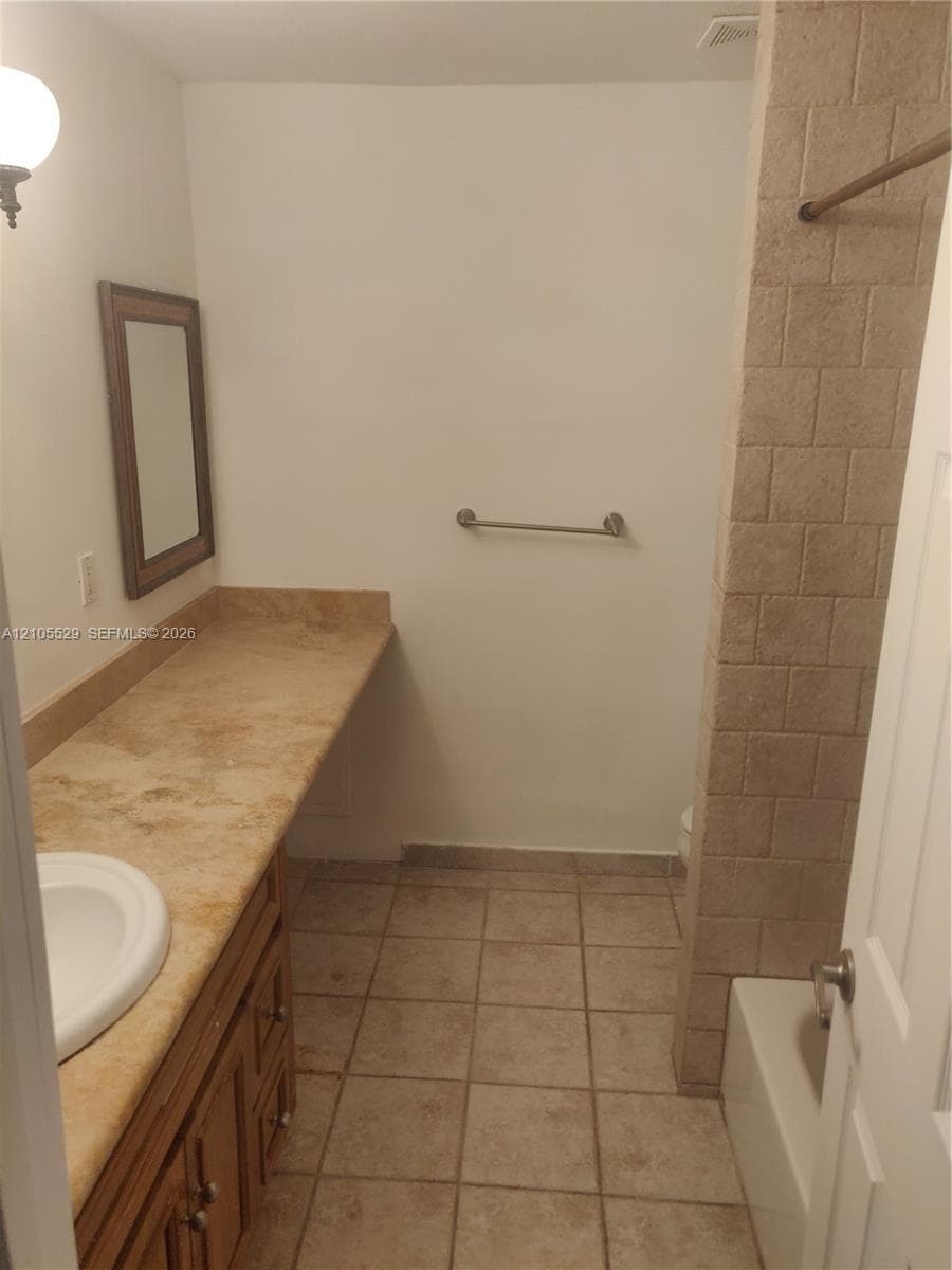 Bathroom featuring a built-in vanity with a sink, extended countertop, wood-finish cabinetry, and a framed mirror
