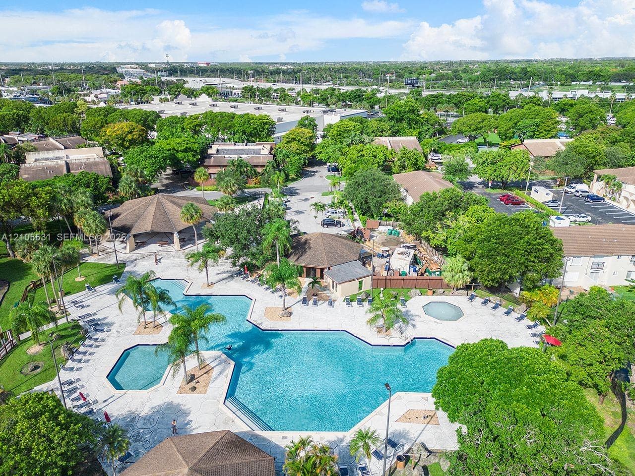 Expansive outdoor amenity area featuring a large, multi-section swimming pool and a separate spa