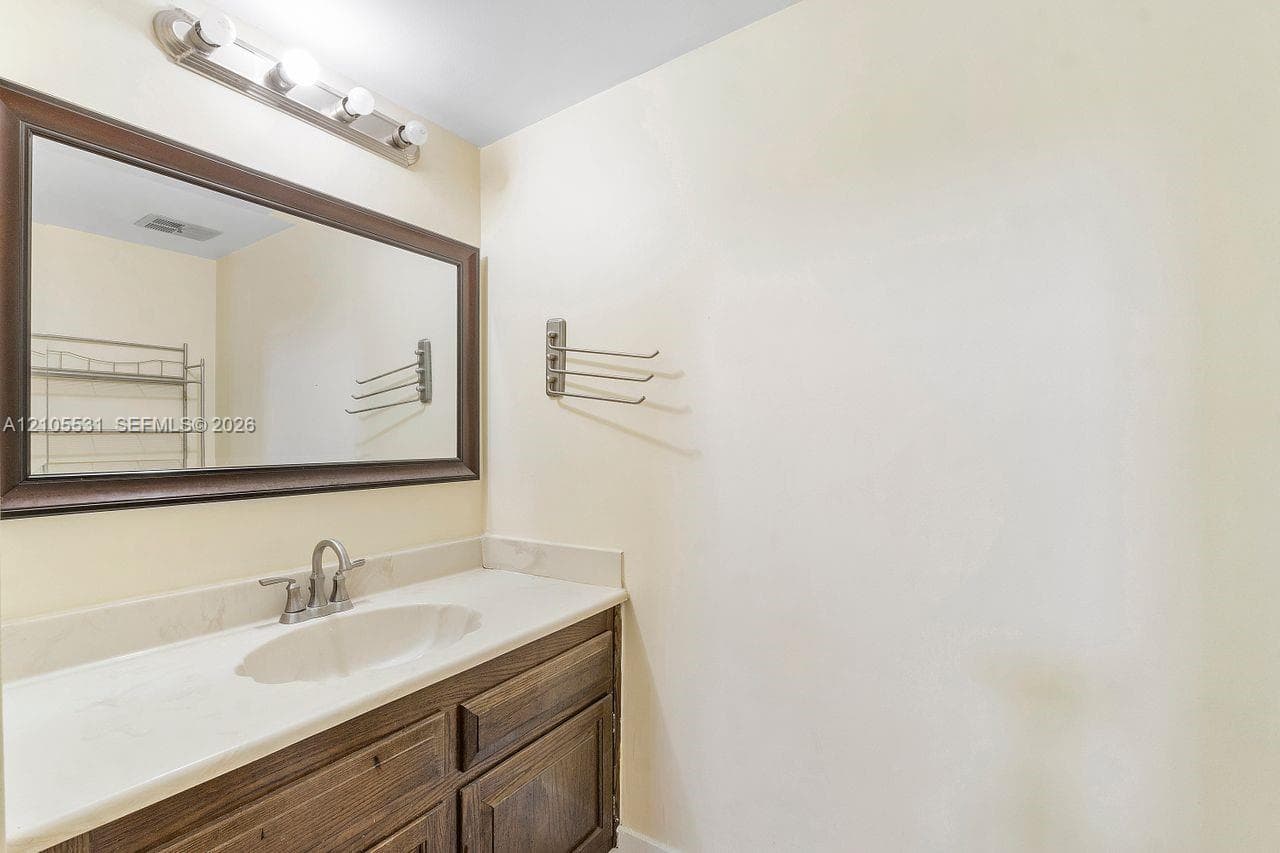 Vanity with wood-finish cabinetry, integrated sink, and light-toned countertop
