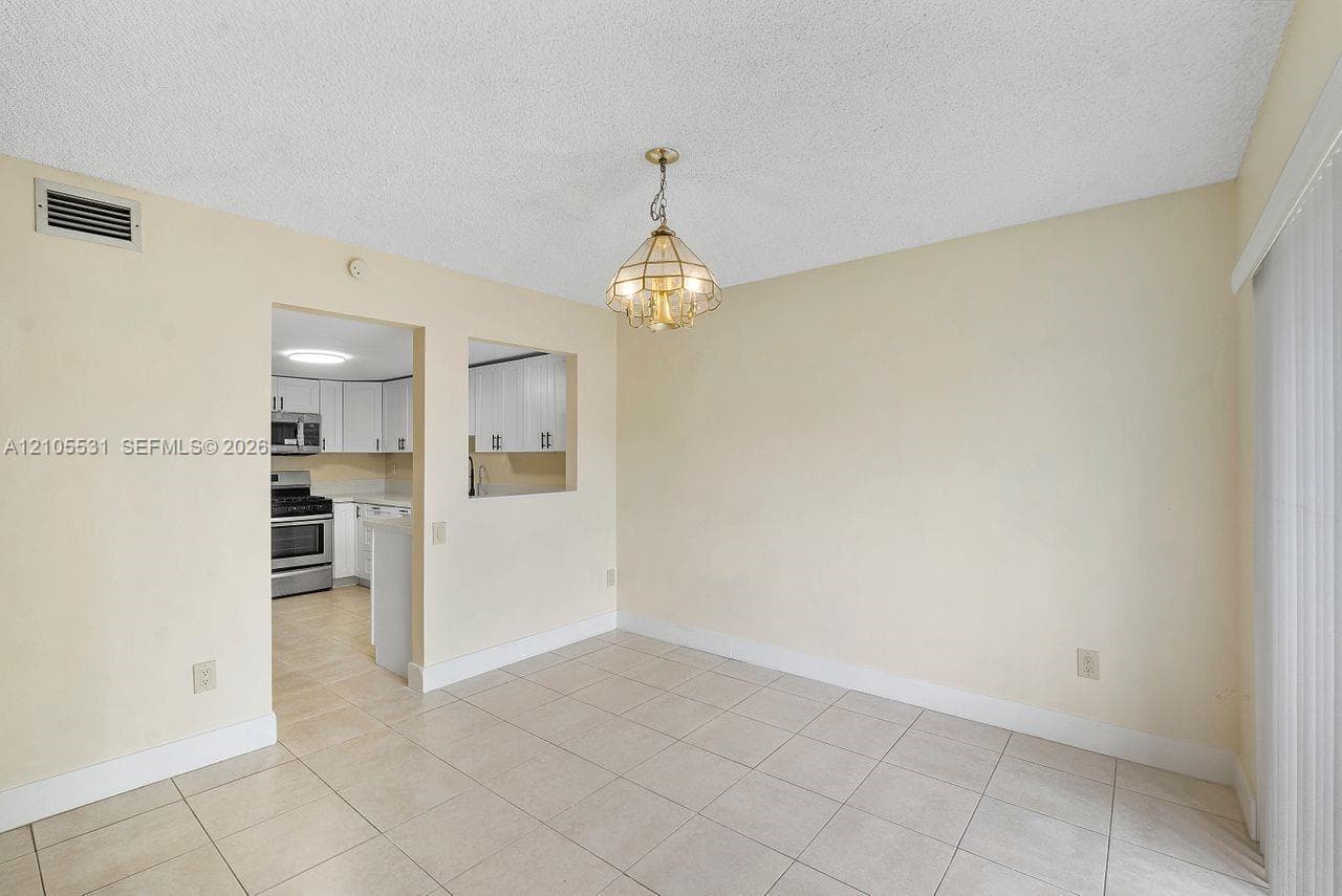 Recessed kitchen with white cabinetry, stainless steel appliances, and a pass-through window