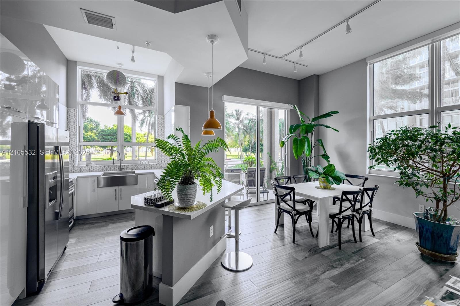 Kitchen featuring wood-finish flooring, quartz-surfaced island, stainless steel farmhouse sink, and high-reaching windows