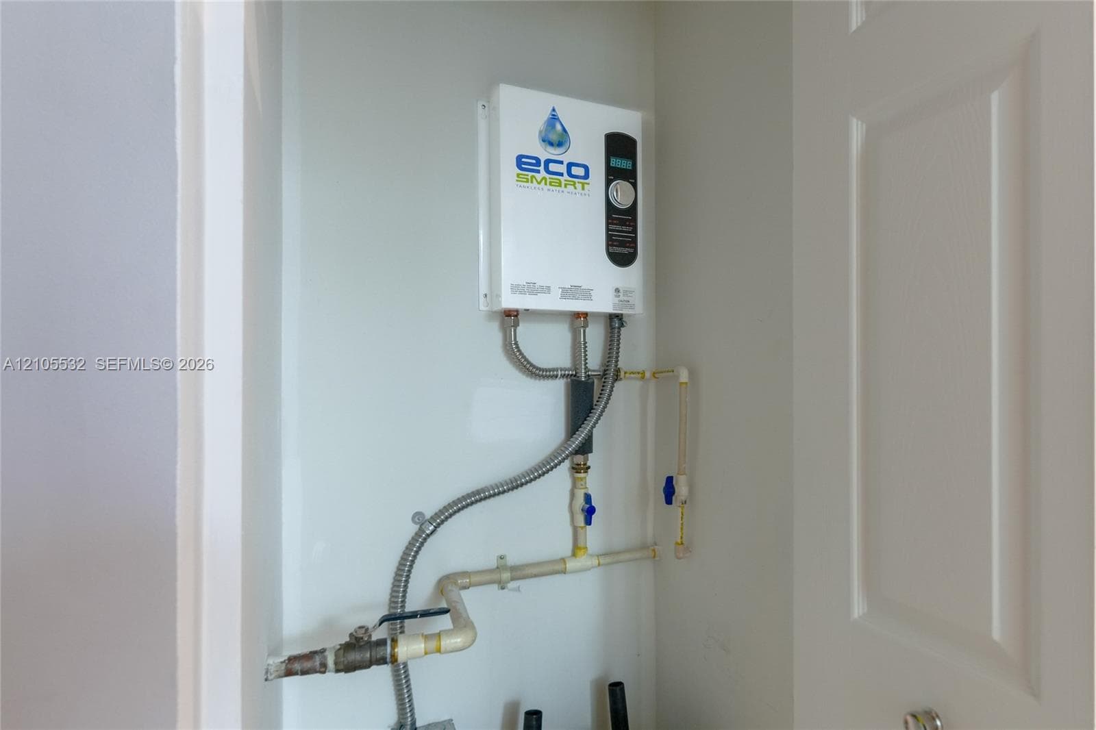 Tankless electric water heating system featuring a digital temperature control interface and integrated plumbing connections