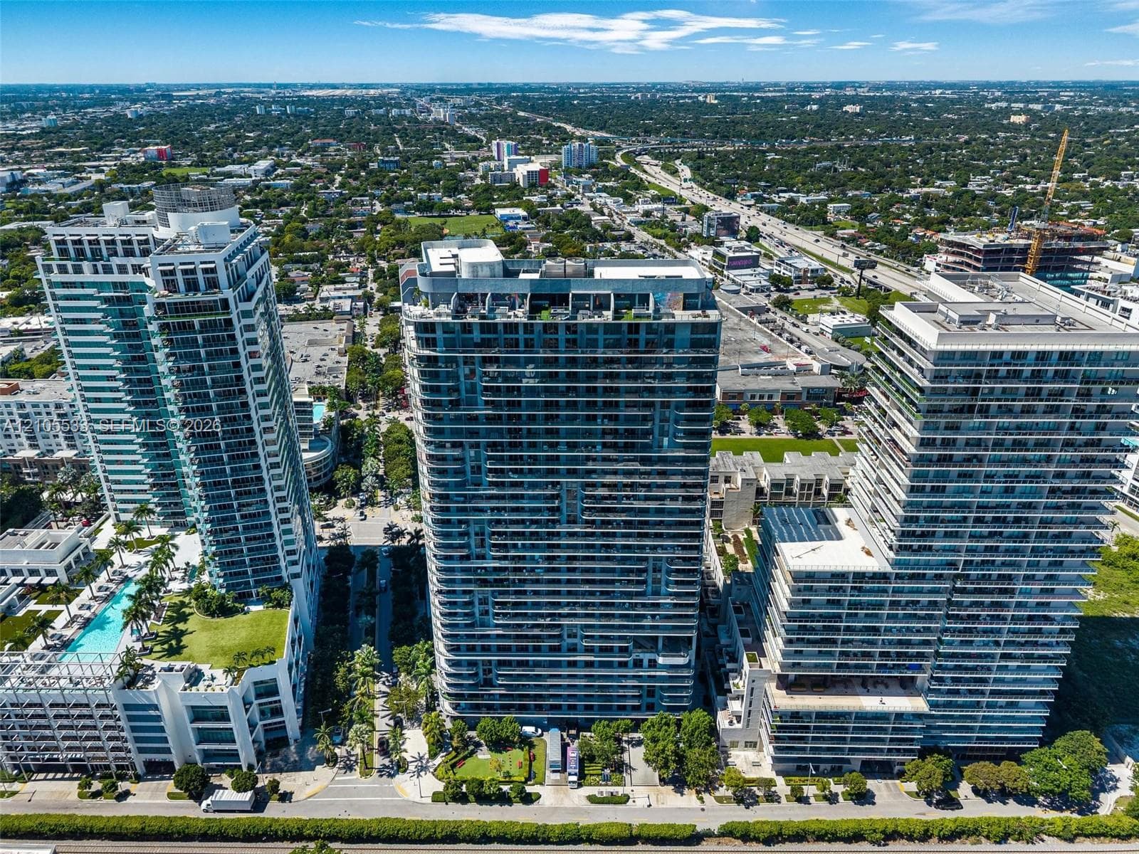 Aerial perspective of urban high-rise towers featuring glass-paneled facades, expansive floor-to-ceiling balcony railings, flat roofs, and integrated ground-level landscaping