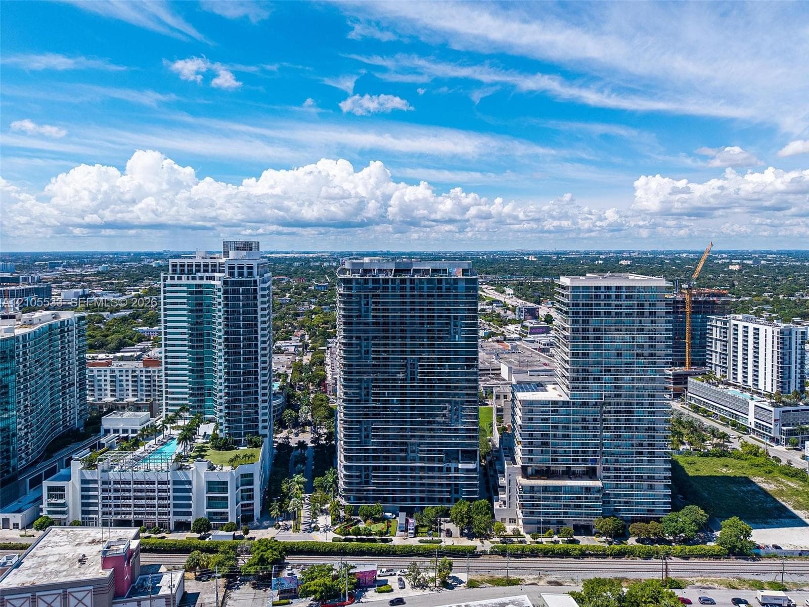 Aerial perspective of a high-rise urban landscape featuring glass-facade residential towers, expansive horizontal balconies, and incorporated podium-level parking structures
