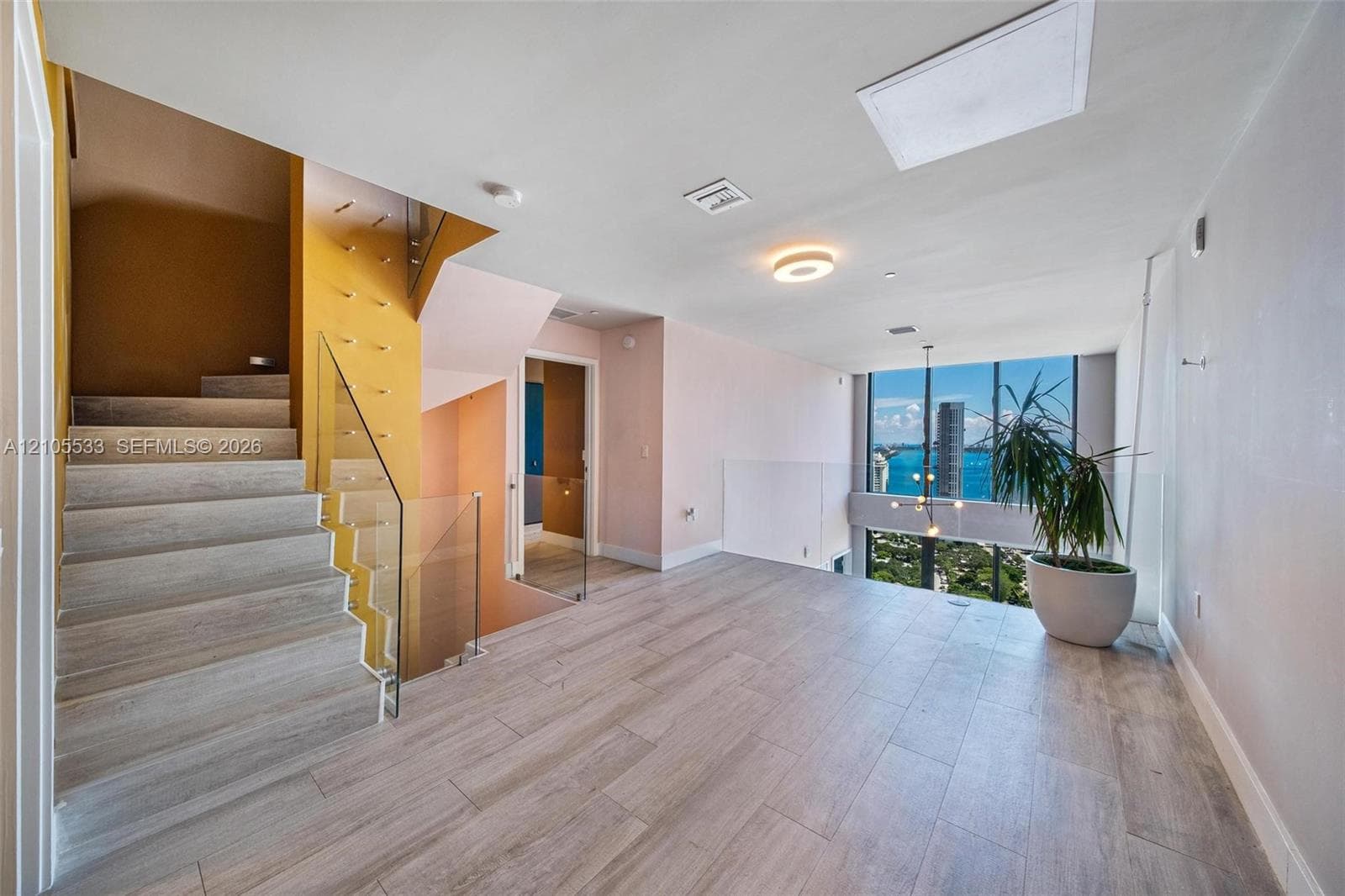Staircase with wood-finish treads, glass railing, floor-to-ceiling windows, and wood-finish flooring