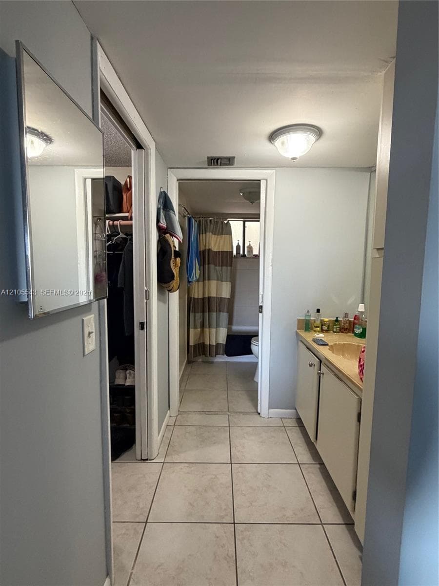 Ceramic tile flooring, vanity cabinet with integrated countertop, wall-mounted mirror, and flush-mount ceiling lighting