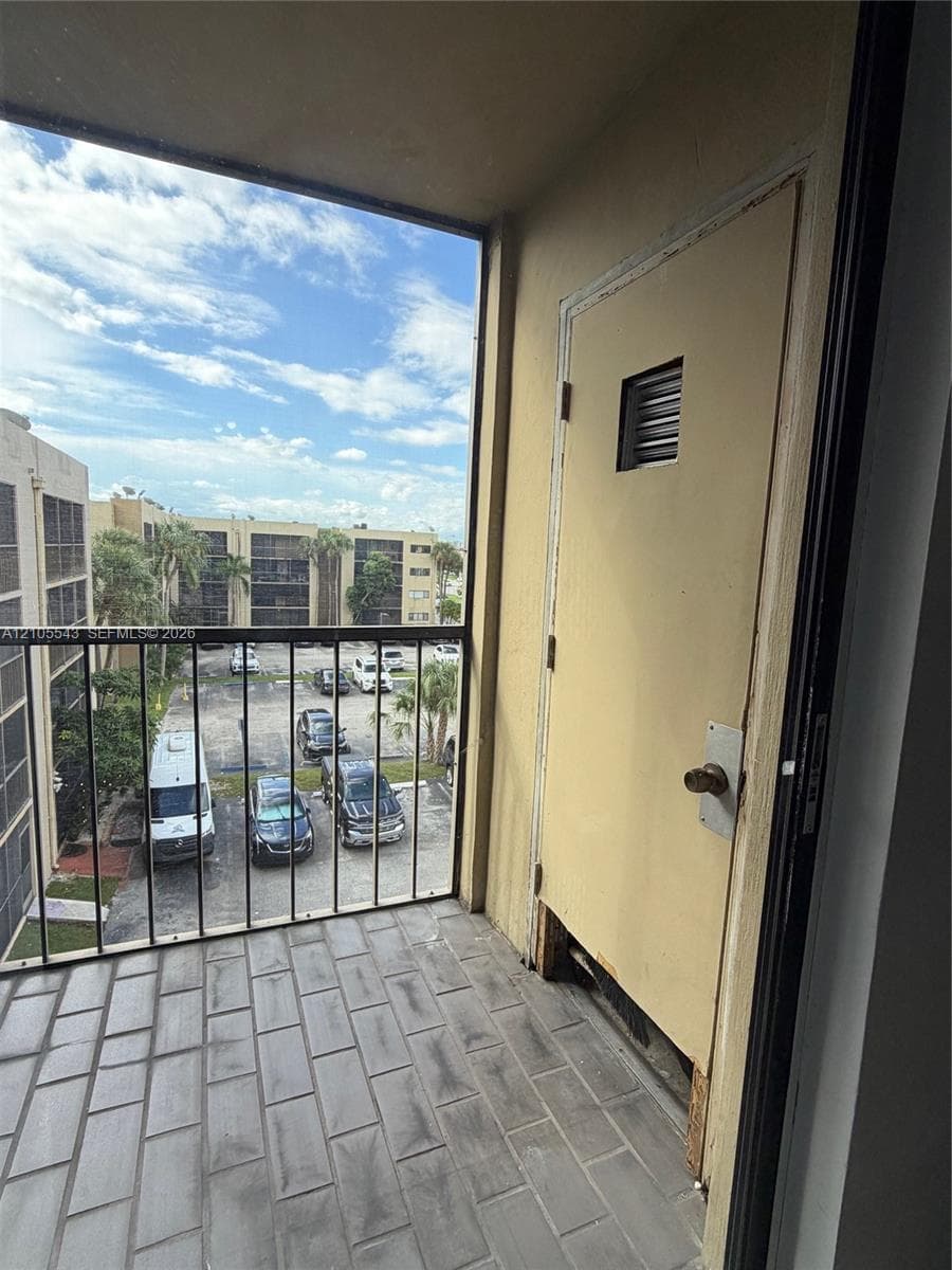 Private balcony featuring grey brick-patterned tile flooring and metal safety railing