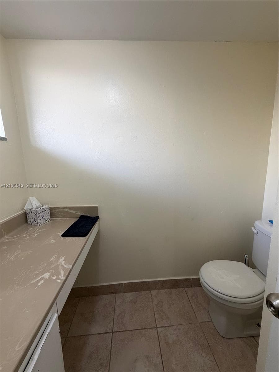 Built-in vanity featuring a stone-composite countertop and ceramic tile flooring