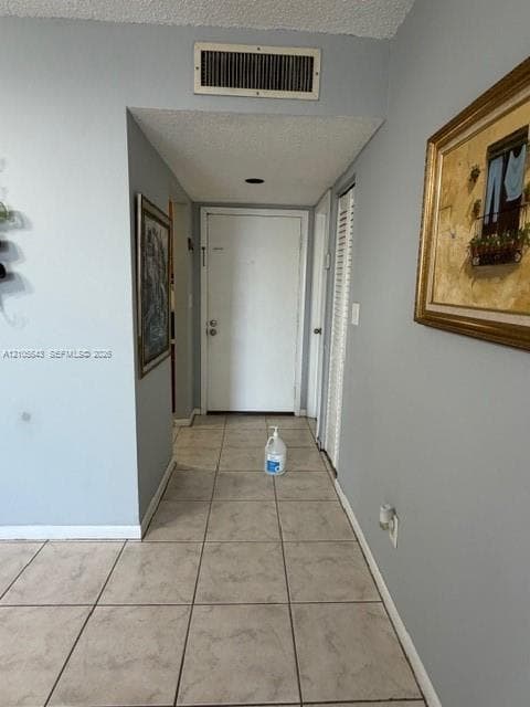 Entryway featuring neutral-toned tile flooring, a solid core door, and louvered closet doors