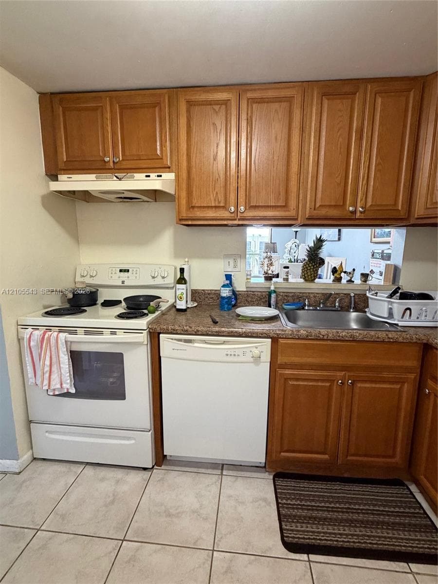 Kitchen featuring wood cabinetry, stone-patterned laminate countertops, white electric range, integrated dishwasher, and tile flooring