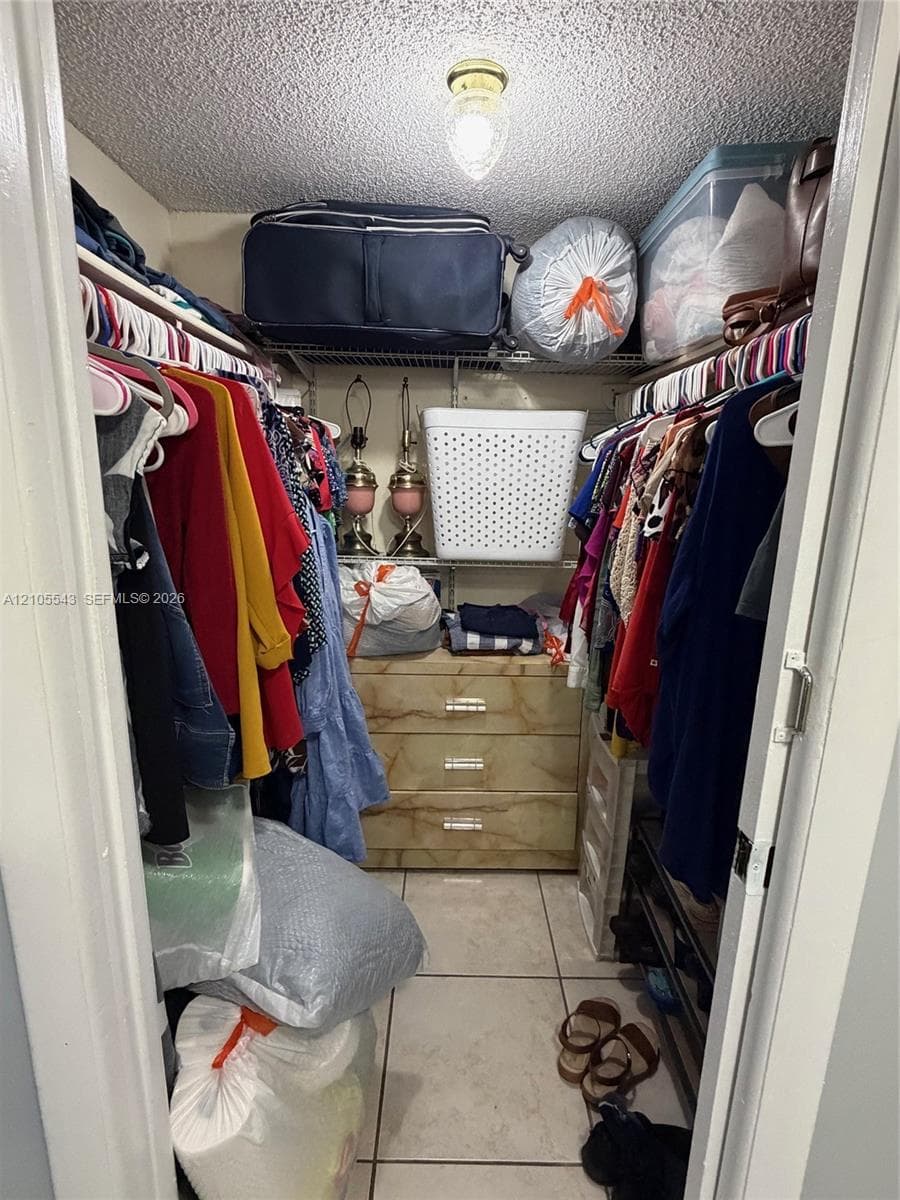 Reach-in closet featuring wire shelving, tile flooring, and a central ceiling-mounted light fixture