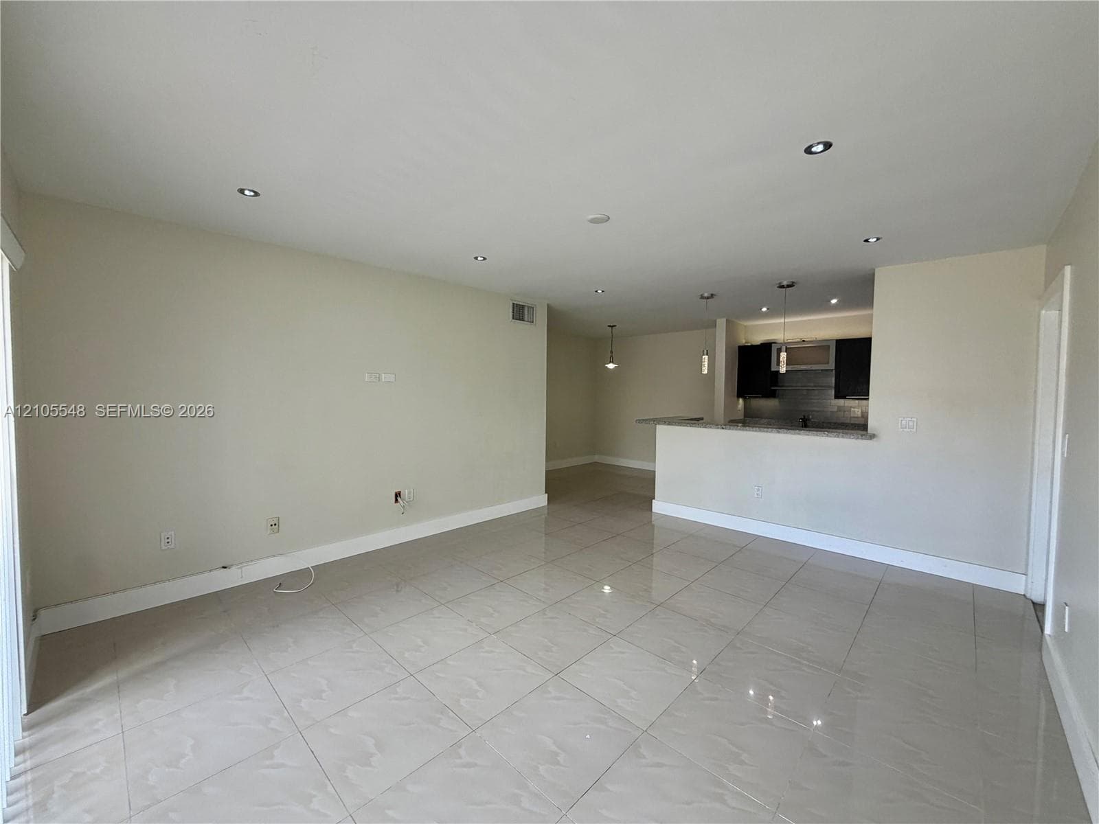 Large-format tile flooring, recessed ceiling lighting, and a kitchen featuring a breakfast bar with granite countertop and modern cabinetry