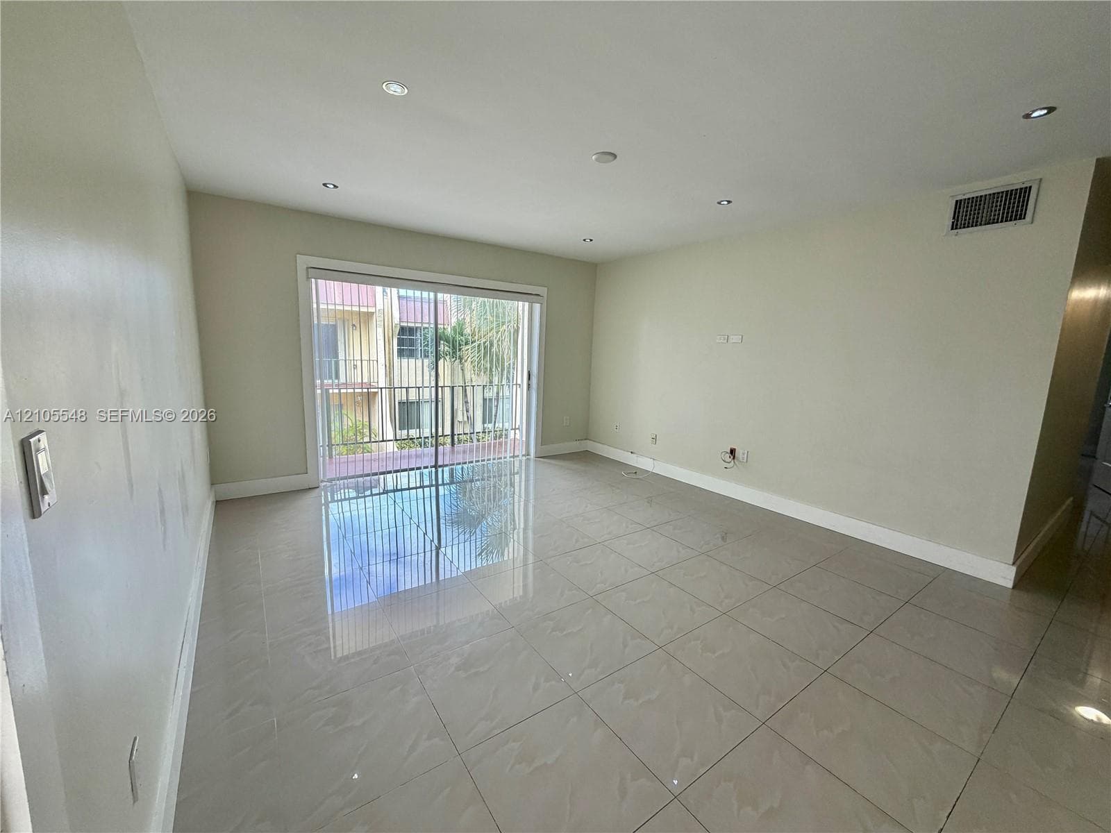 Interior space featuring large-format porcelain tile flooring, recessed lighting, and a floor-to-ceiling sliding glass door providing external access to balcony