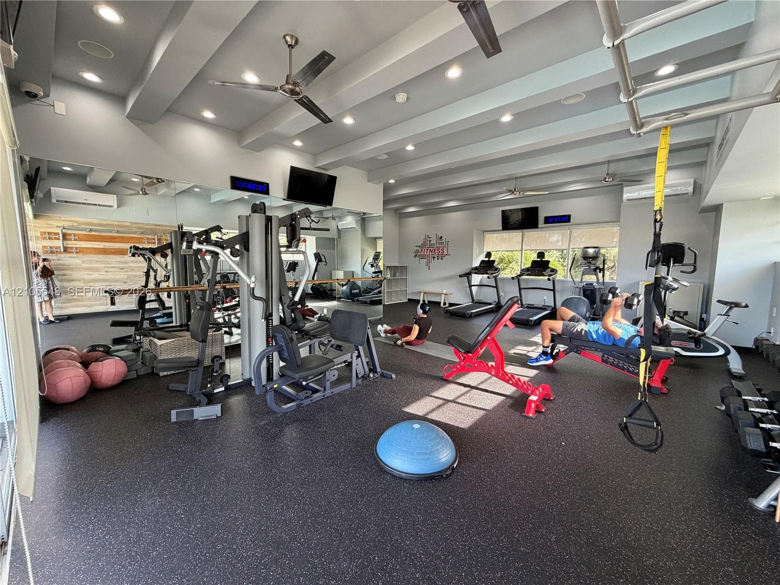 Gym featuring rubber flooring, recessed ceiling lighting, full-wall mirrors, and floor-to-ceiling glass windows