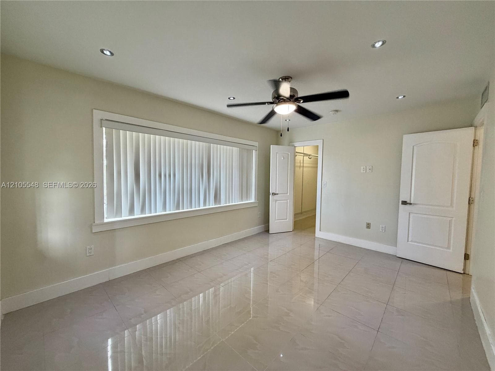 Spacious room featuring polished porcelain tile flooring, recessed lighting, a ceiling fan with integrated light fixture, and two panel-style doors