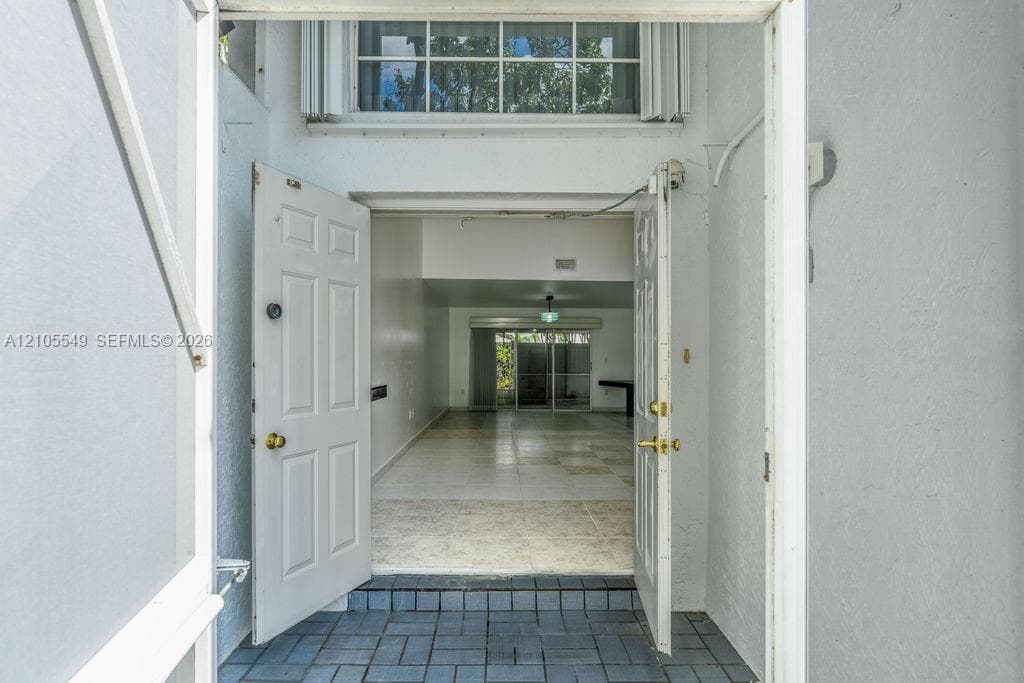 Entryway featuring a panel door, tiled flooring, and an overhead window