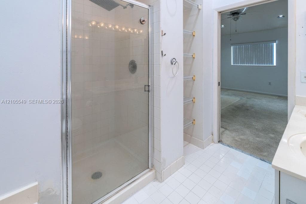 Walk-in shower with clear glass enclosure and overhead lighting