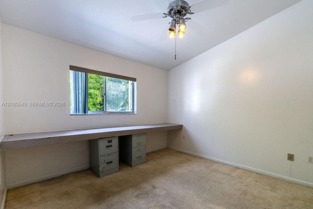 Recessed window with horizontal blinds, built-in desk counter, and ceiling fan with integrated lighting