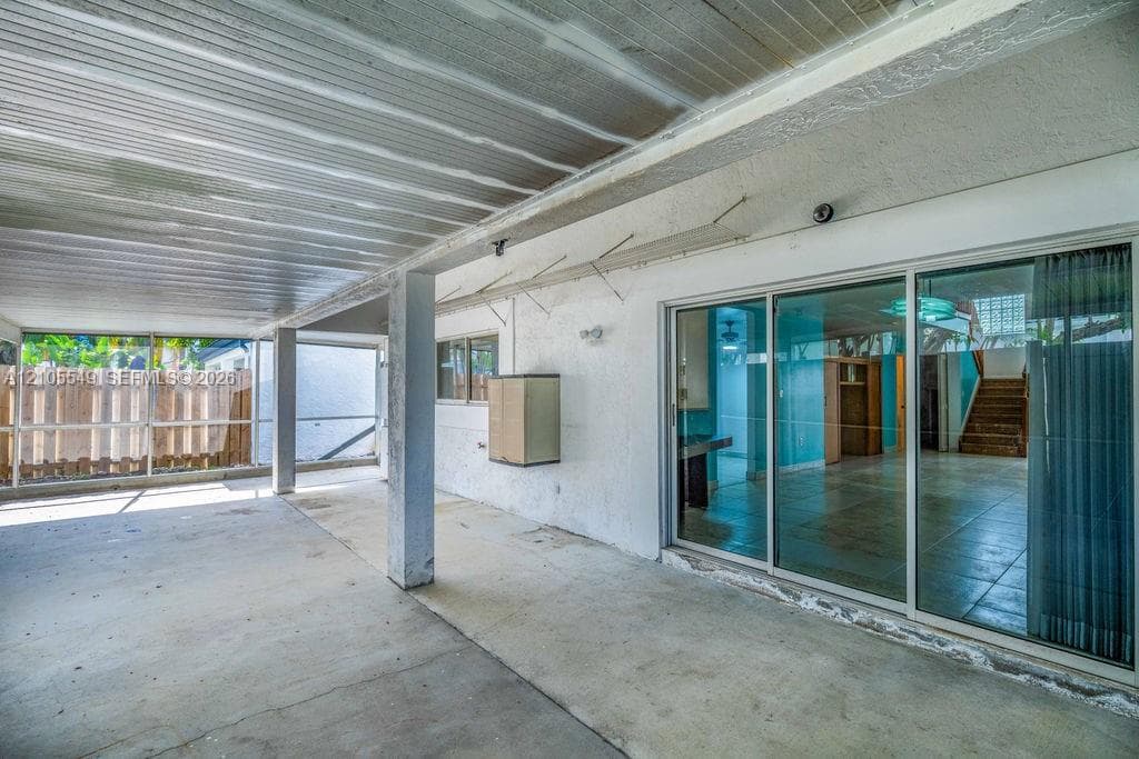 Covered concrete patio with a slatted ceiling, a concrete floor, and multiple support columns