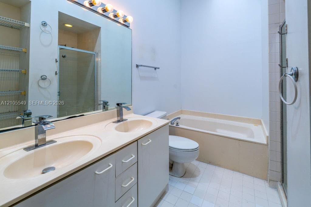 Dual vanity with integrated sinks, built-in bathtub, and an adjacent shower enclosure