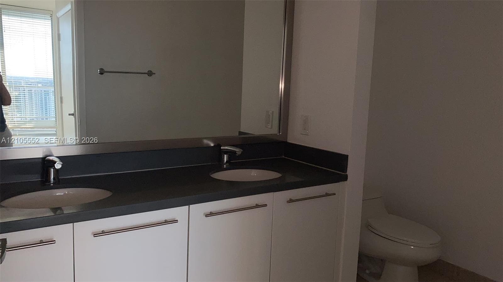 Double vanity with integrated sinks, contemporary faucets, and a dark countertop