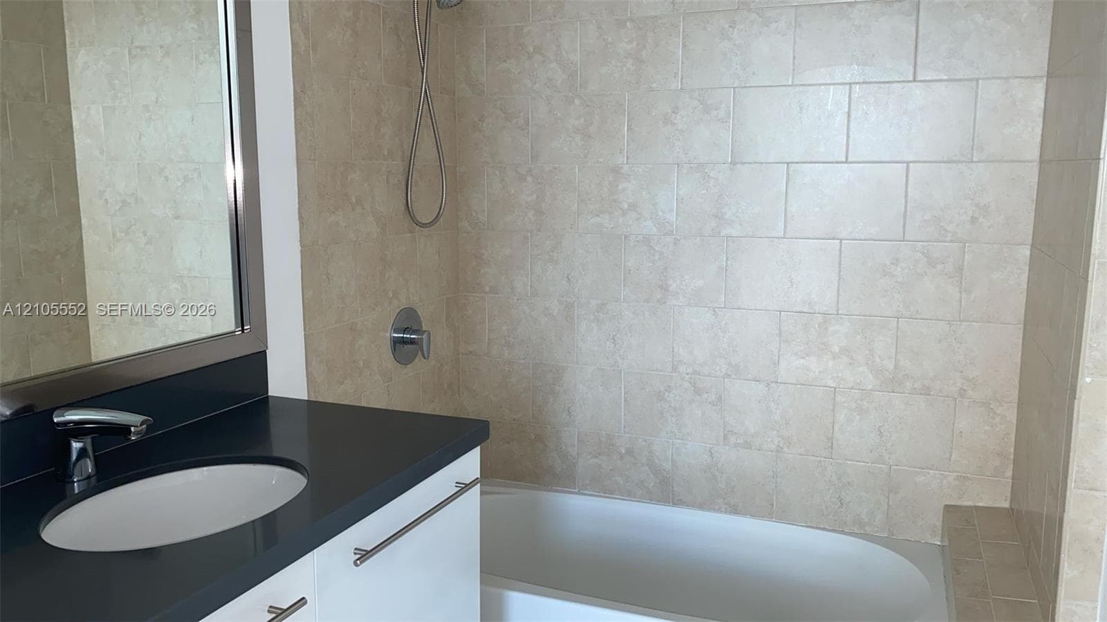 Built-in vanity with a dark countertop, undermount sink, and polished chrome faucet