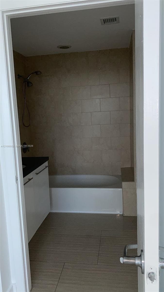 Recessed lighting illuminates the tiled shower/tub combination with a built-in bench