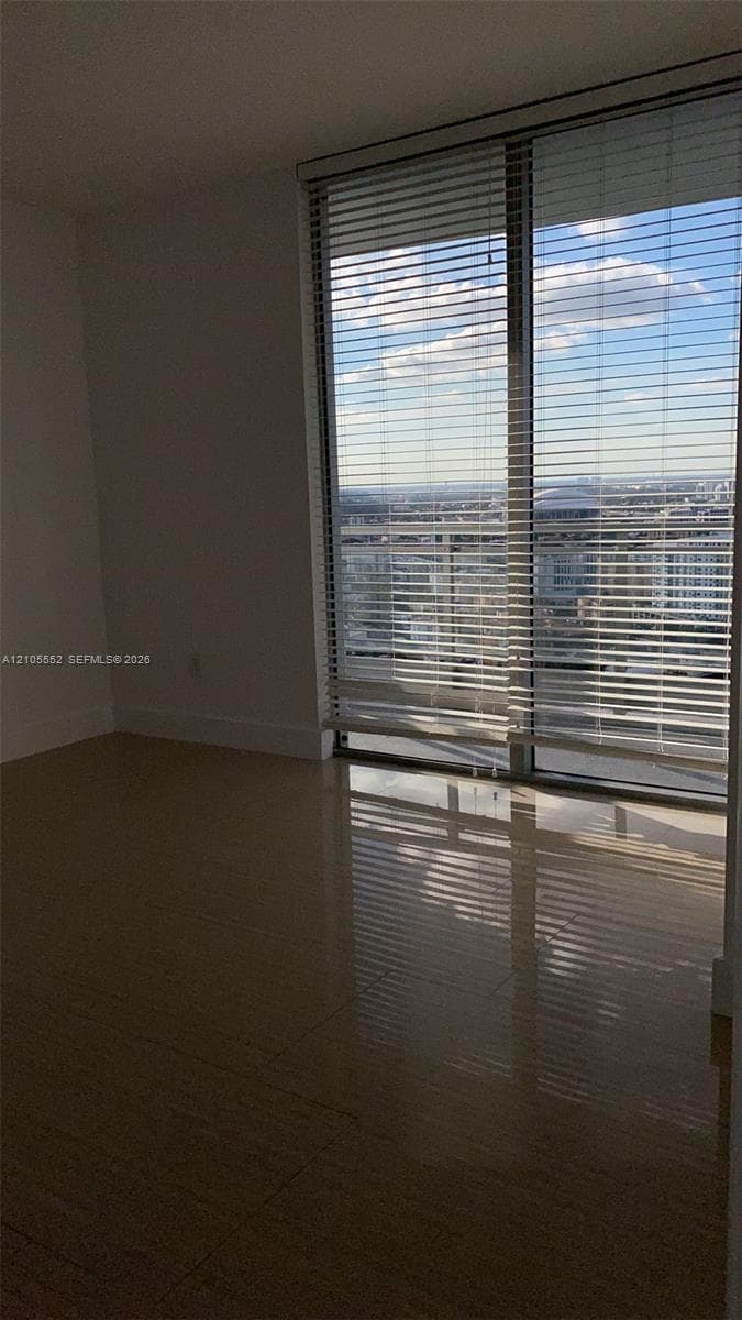 Floor-to-ceiling sliding glass doors with horizontal blinds, showcasing an expansive cityscape and distant horizon