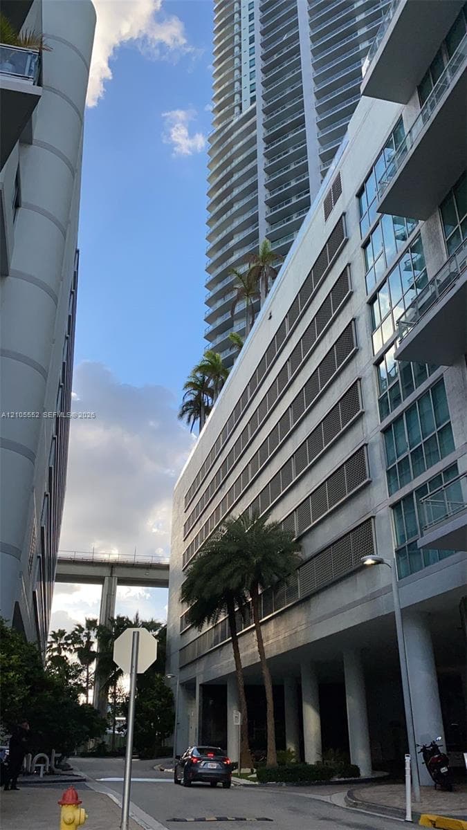 Multiple high-rise structures featuring balconies, palm trees, and a concrete overpass