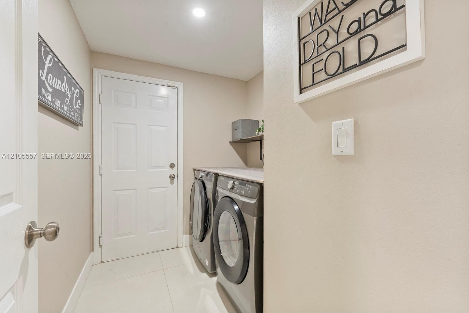 Laundry area featuring white paneled doors, tile flooring, a built-in shelf, and recessed lighting