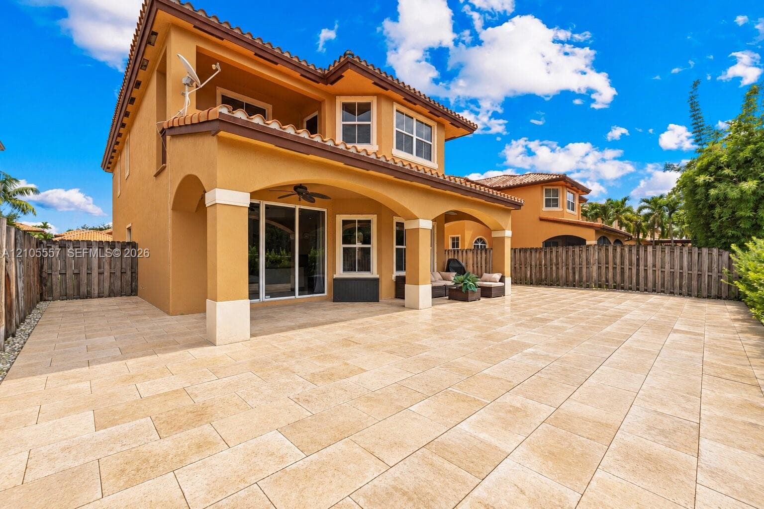 Expansive paved patio with a covered outdoor living area featuring a ceiling fan