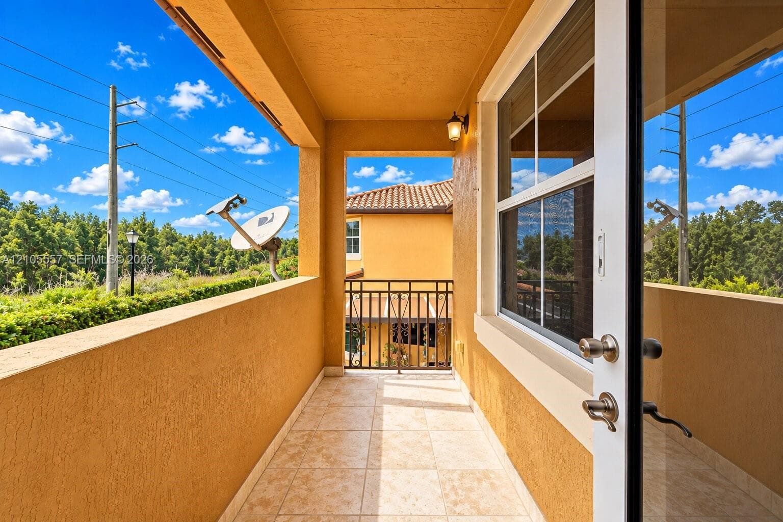 Outdoor balcony with tile flooring, stucco exterior, and a wrought iron railing