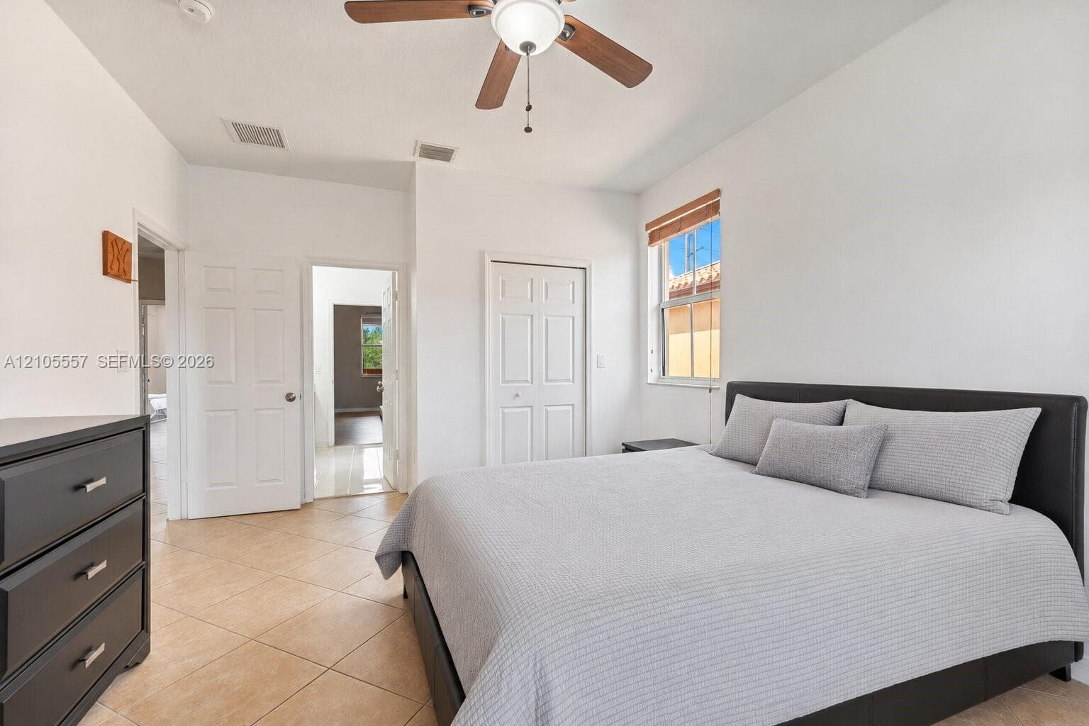 White interior walls with a sloped ceiling, wood-finish ceiling fan, and tiled flooring