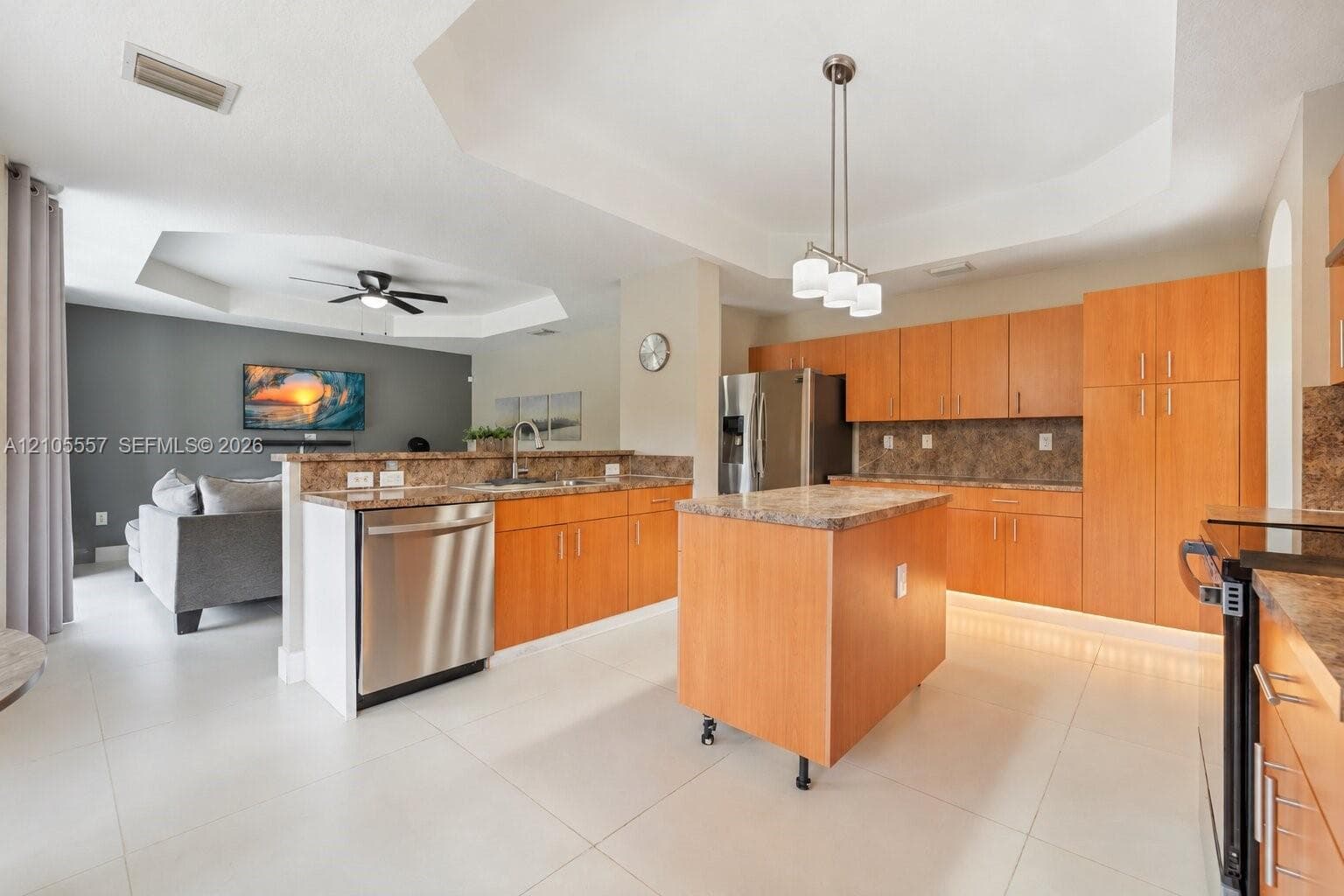 Open-concept kitchen with light wood-finish cabinetry, stone countertops, and stainless steel appliances