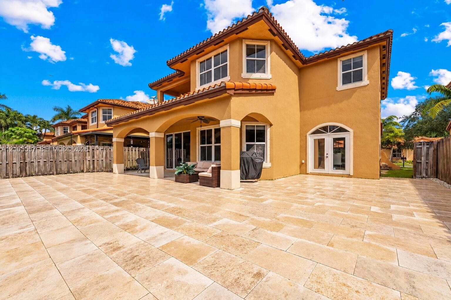 Expansive outdoor patio with large format pavers, covered lanai, multiple access points, and stucco exterior