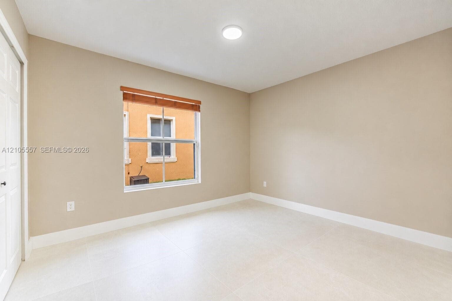 Recessed lighting, neutral wall tones, large window, wood-finish window treatments, and light-toned tile flooring