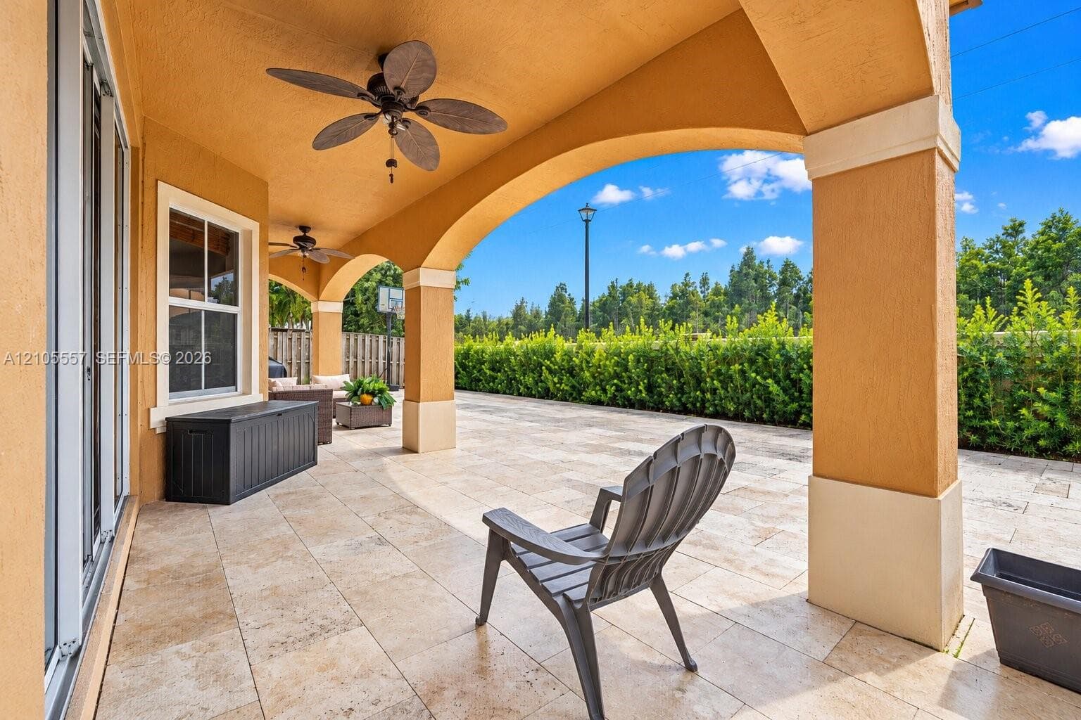 Covered patio featuring an arched entryway, ceiling fans, and tiled flooring