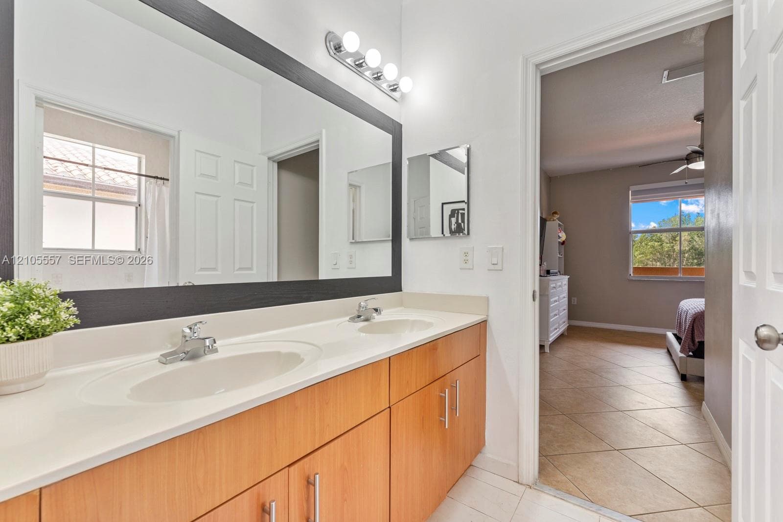 Dual vanity with integrated sinks, wood-finish cabinetry, and a large wall-mounted mirror