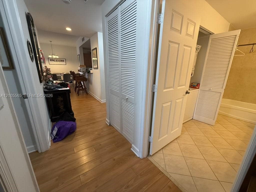 Wood-finish flooring, white louvered closet doors, and ceramic tile flooring