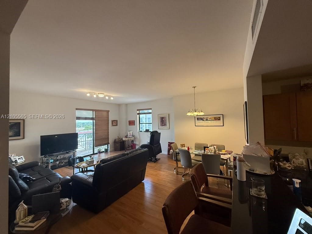 Open-concept interior featuring wood-finish flooring, a breakfast bar with stone-finish surfacing, and multiple windows