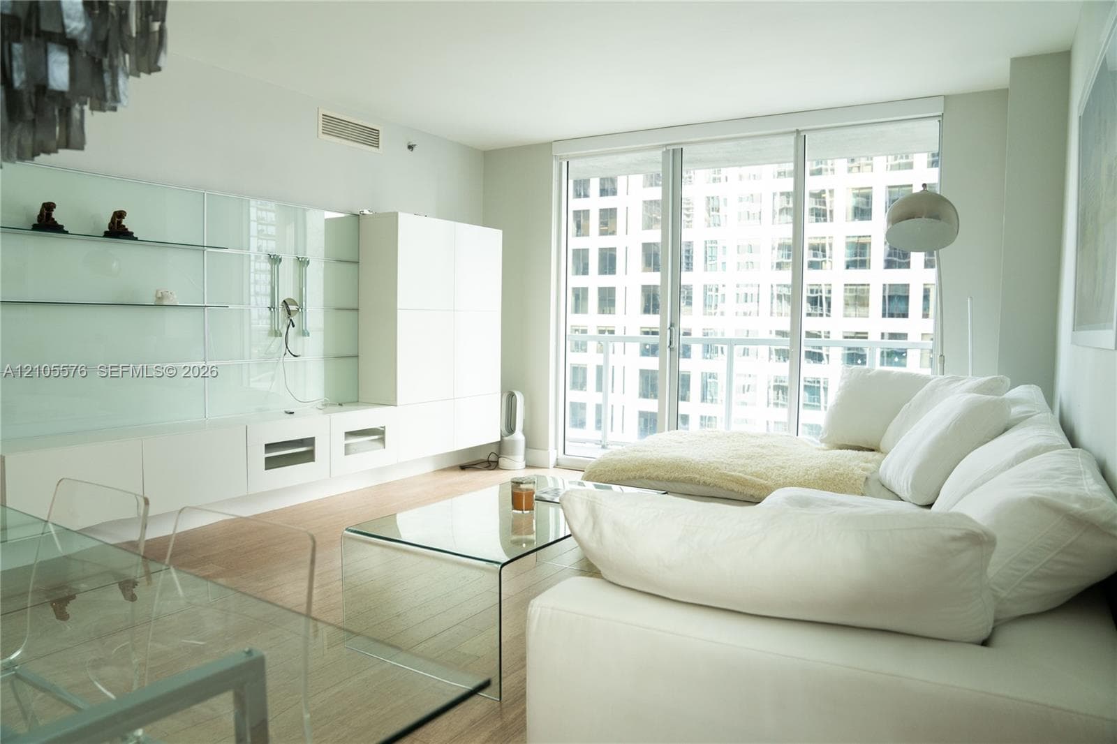 Living area featuring floor-to-ceiling glass sliding doors, built-in white cabinetry with glass shelving, wood-finish flooring, and recessed ceiling lighting