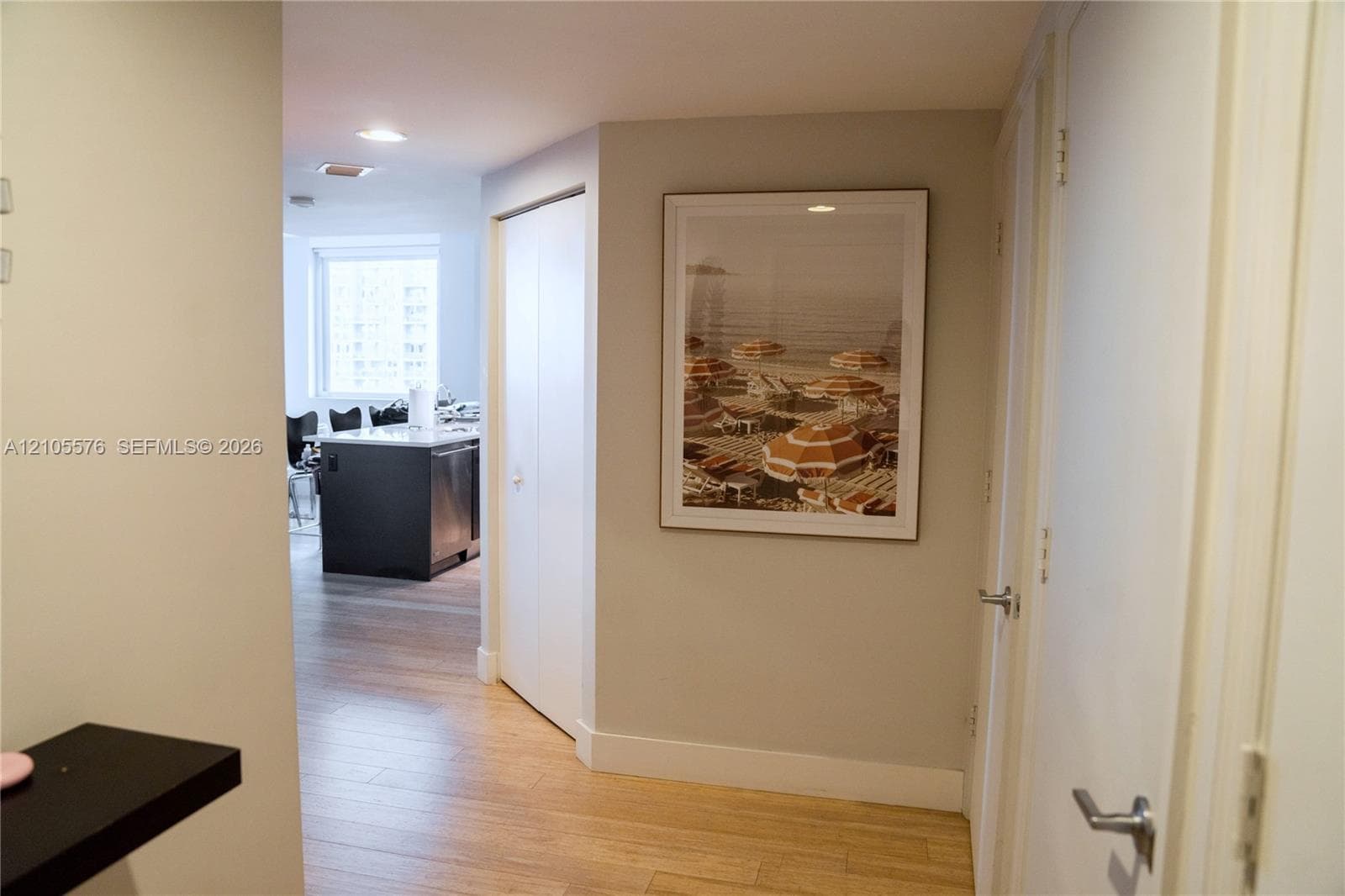 Neutral-toned interior featuring wood-finish flooring, recessed lighting, and white interior doors with contemporary metallic hardware