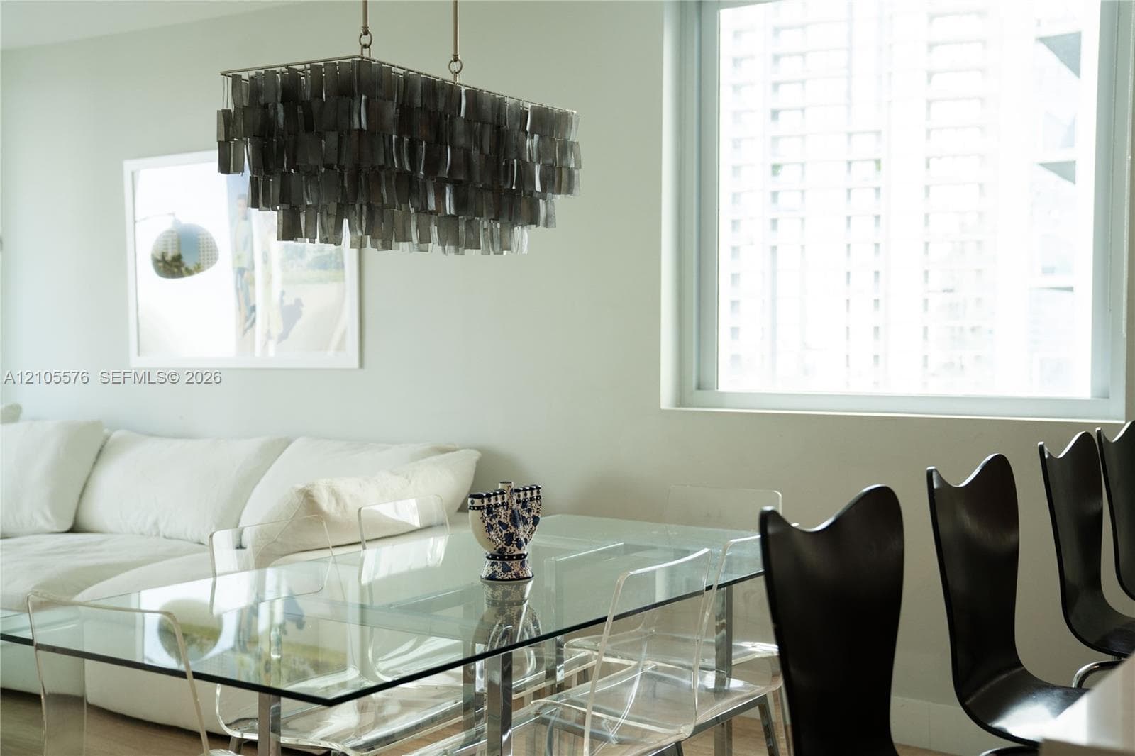 Rectangular tiered chandelier with dark metallic finish and large, expansive window with aluminum framing