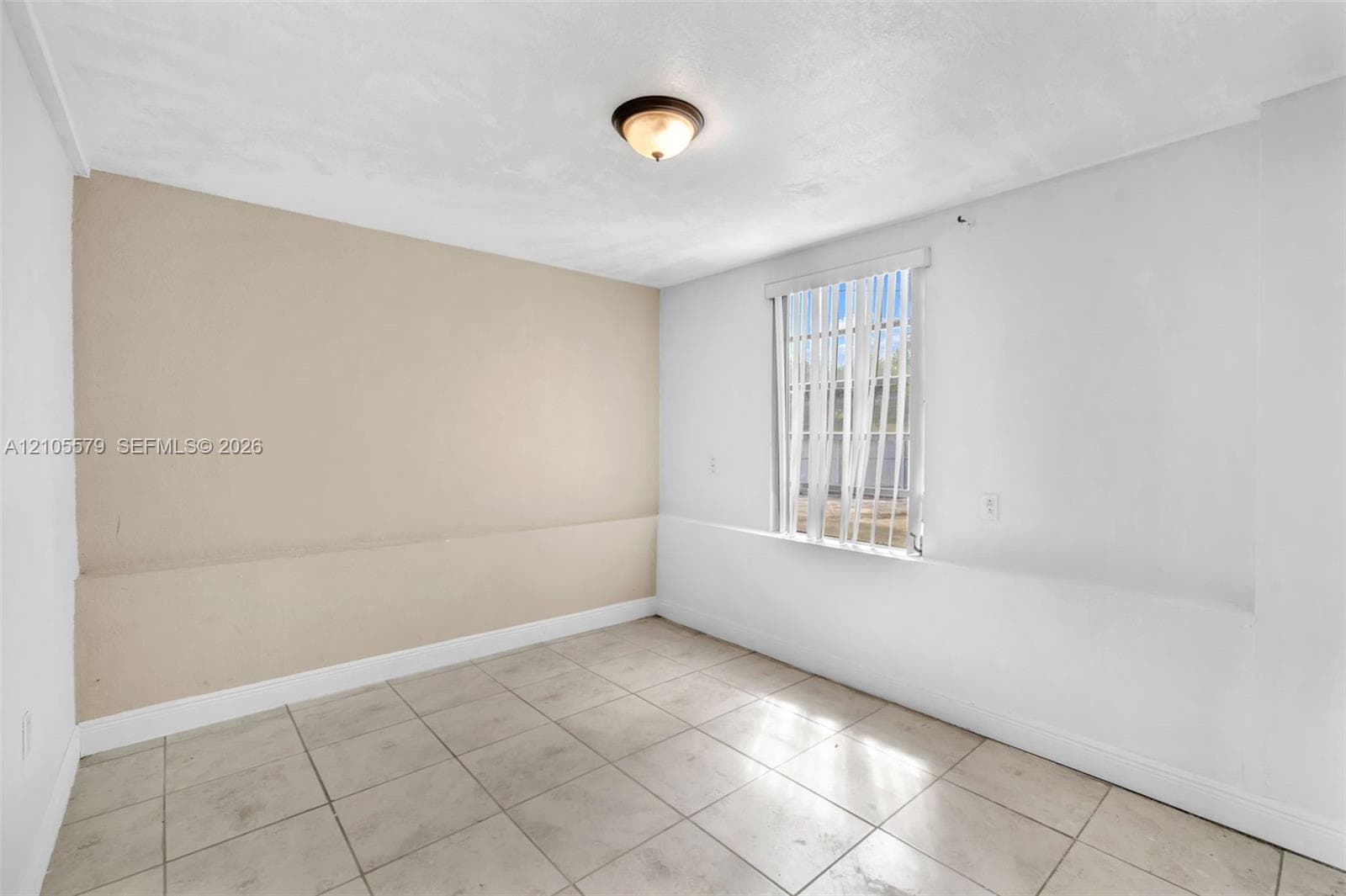 Neutral-toned interior space featuring tile flooring, a dual-tone wall finish, and a flush-mount ceiling light