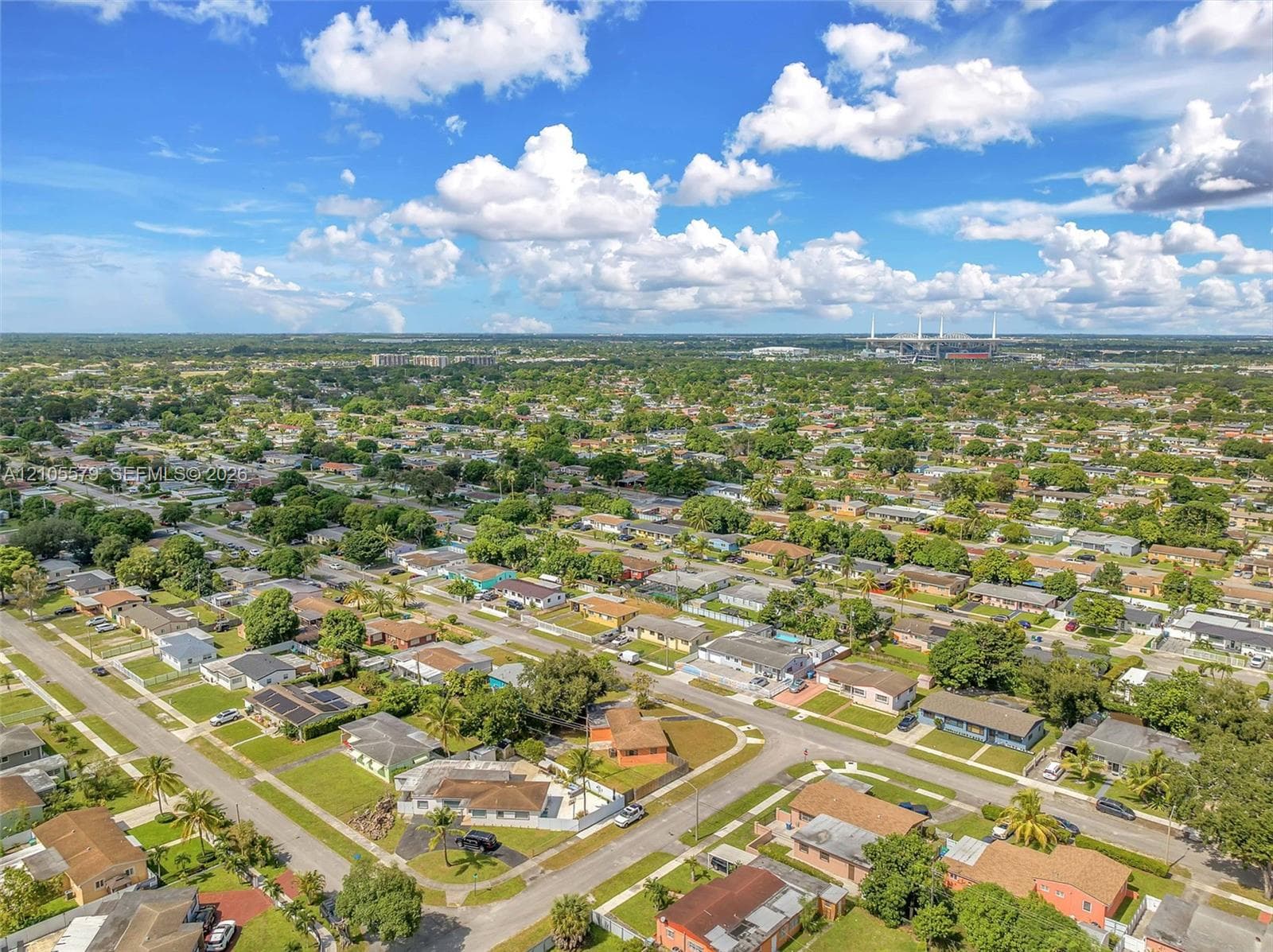 Aerial perspective of a residential landscape featuring mature trees, grid-patterned streets, single-story structures, and expansive green space