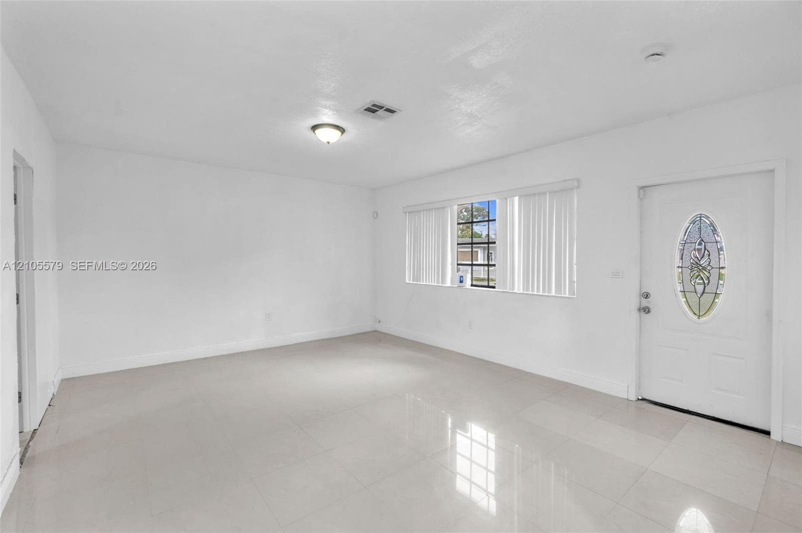 Neutral-toned tile flooring, large multi-pane windows, and an entry door featuring an oval decorative glass insert